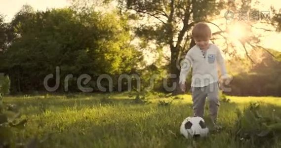 快乐的男孩在日落时分用足球奔跑视频