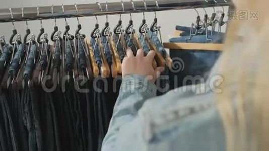 各种各样的女人`牛仔裤挂在衣架上。 女人在商店里挑选衣服。 双手合拢视频