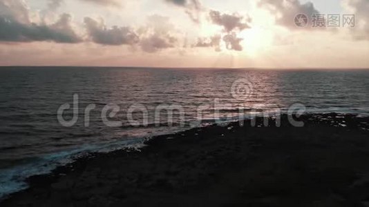 一张美丽的粉红色日落，海浪拍打着岩石海滩视频