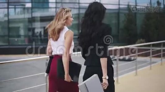 商业女性在商业中心的背景下使用文件夹。 两个穿着严格西装的女孩。 回来视频