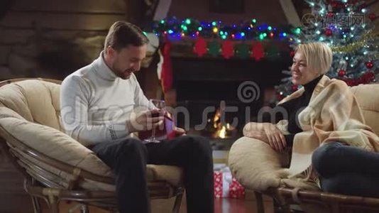 男人把一杯酒递给妻子，打开圣诞礼物视频