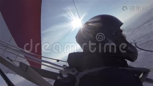 一架悬挂式滑翔机在阳光明媚的天空中飞过一片白雪皑皑的冬季草地和森林。视频