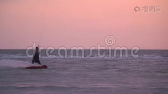 这名男子控制着一只训练风筝，背景是日落，慢镜头拍摄视频