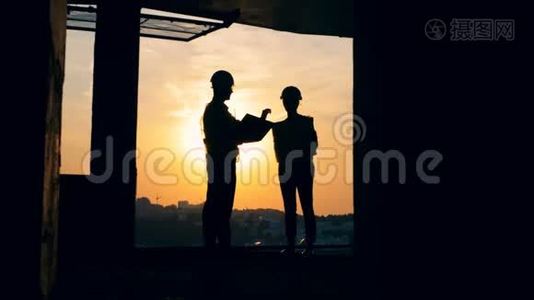 一名男性和一名女性工程师站在一栋多层建筑中的剪影，建筑工地视频