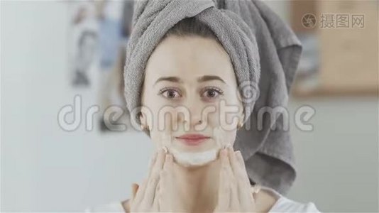 头上戴毛巾的女人戴上化妆面具看着镜头视频