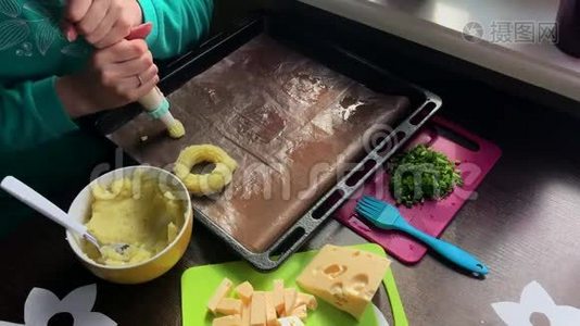 一个女人在烤盘上形成土豆圈。 借助糕点包.. 奶酪、洋葱片和炸蘑菇都在上面视频