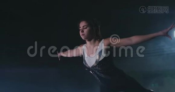 在烟雾中缓慢运动，一个女运动员站着，她的手臂举起后，表演练习。 欢迎手势视频