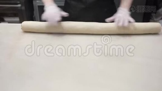 场景：库克将包裹好的面团与肉桂馅料在一卷中对齐。 生产肉桂卷。 面包制品视频
