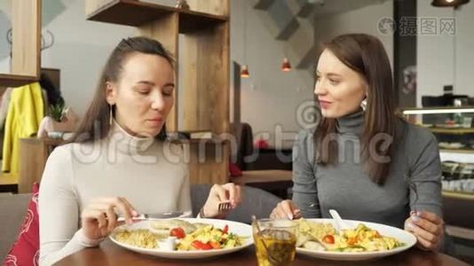 两个女朋友在咖啡馆里一起吃饭，聊天，享受他们的食物。视频