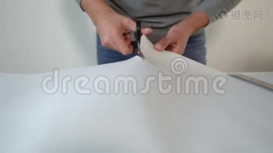 特写男手在桌子上用剪刀剪下新的弯曲壁纸卷视频