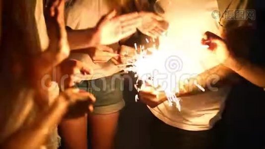 朋友们在海边的夜间聚会中站在较轻的火堆旁，用手点燃孟加拉火花灯视频