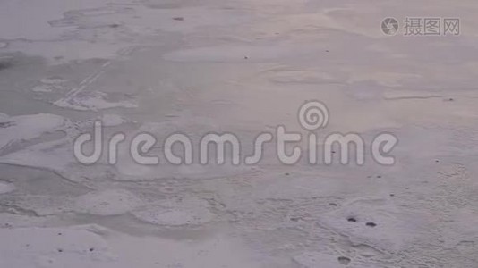一条覆盖着雪的冰冻河流的特写，上面有脚印。视频