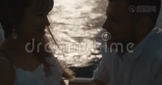 在游艇上恋爱的情侣。 男人亲吻女人`手，而她们坐在游艇上的夕阳下视频