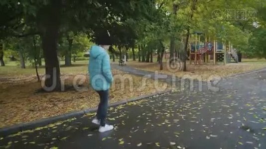 雨天在秋天公园散步的漂亮女孩。视频