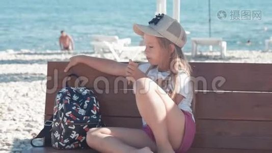 十几岁的女孩在暑假，谈论坐在海边的长凳上吃冰淇淋。 孩子们在海滩上吃冰淇淋。视频