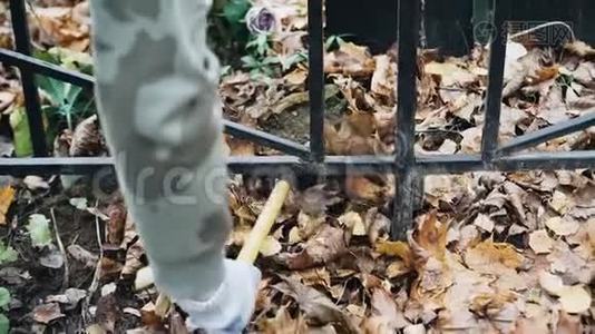 一个女人用耙子把落叶从院子里移走。 快关门。视频