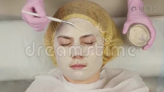 美容师把面膜敷在问题皮肤上。 年轻女子有皮肤清洁程序。 4K视频