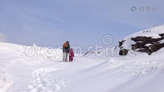 在一个寒冷的冬天，母女俩在一条下雪的小路上爬上了山。视频