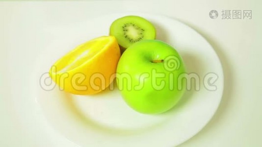 白色盘子里的橙皮猕猴桃和绿皮苹果的两半旋转成一个圆圈视频