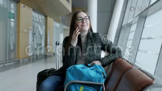 幸福的女人正在用手机聊天，等待她在机场的航班。视频
