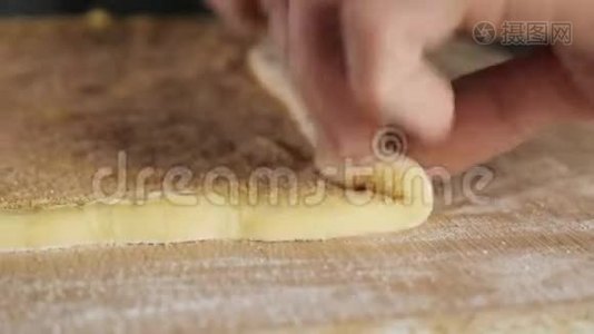面包师用肉桂、糖和黄油将面团卷成一卷在桌子上。视频