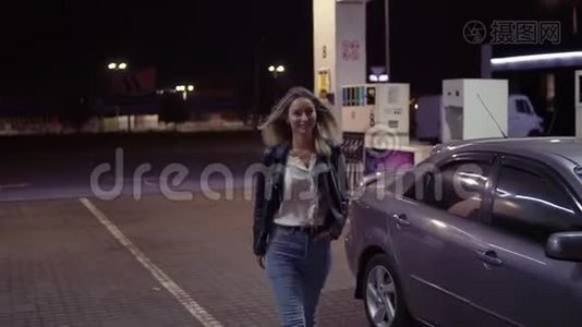 卡瓦尔加油站的浪漫、微笑的女人肖像，背景中的汽车行走和摆姿势。 正面观点视频