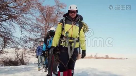 穿着工作服的登山者在人行道上互相跟随，手里拿着登山杖和镐。视频