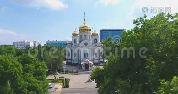 空中运动，带有金色圆顶的正统教堂矗立在图案公园，城市高层建筑背景上有树木视频