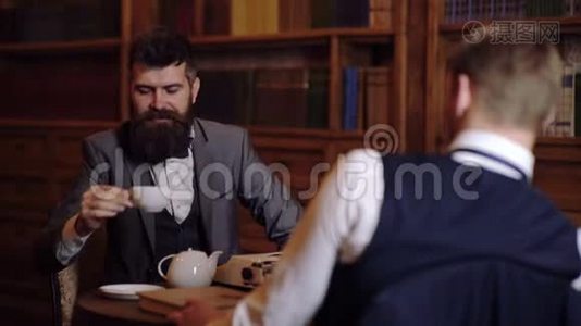 两个可敬而聪明的人在图书馆里交流。 传播的概念.. 两个男人喝咖啡视频