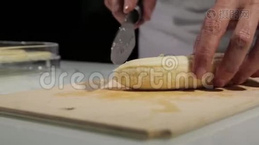 妇女使用菜刀滑动切割香蕉在木切割板上。 香蕉切片处理干果视频