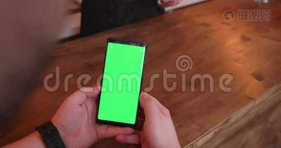酒吧柜台的人拿着一部绿色屏幕的手机视频
