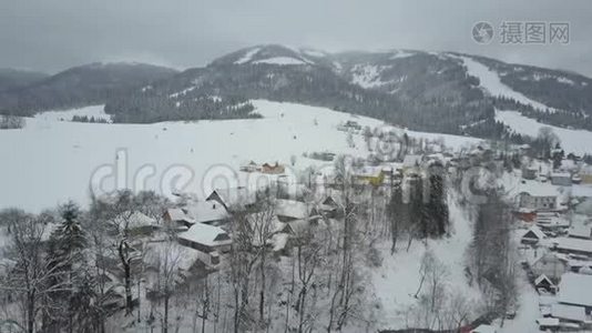 飞越喀尔巴阡山的一个村庄。 鸟`山上白雪覆盖的房子的视野。 乡村景观视频