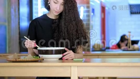 漂亮的亚洲女人在智能手机上自拍。 年轻的亚洲女孩在咖啡厅与pho汤拍照。 中文视频