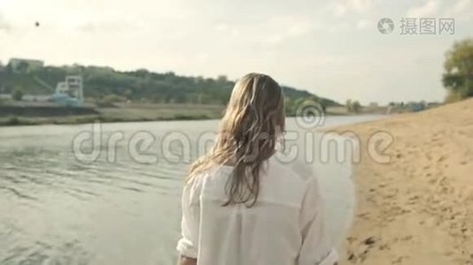 女孩沿着海岸上的水，看着视频