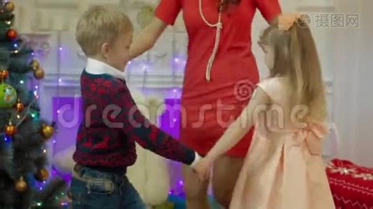 快乐的母亲和孩子们在圣诞树的背景下跳舞视频