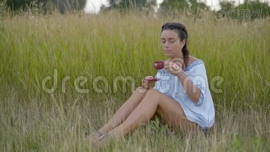美丽的女人在草地上喝咖啡视频