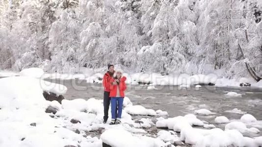 恋爱中的情侣在冬天的河岸边玩得开心，欣赏冬天的大自然。视频