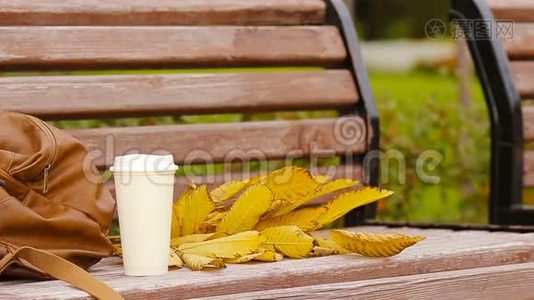 一杯热咖啡和黄色的秋假酒在公园的长凳上视频