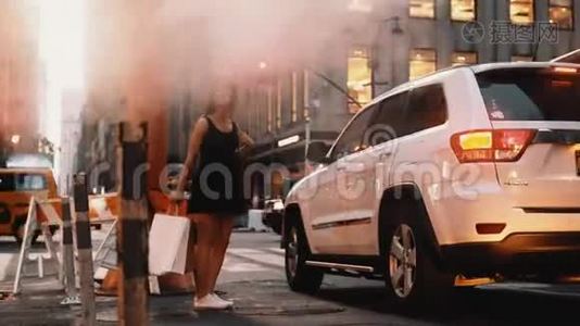 一位年轻的女士，带着购物袋站在美国纽约市中心靠近交通路的烟斗附近。视频