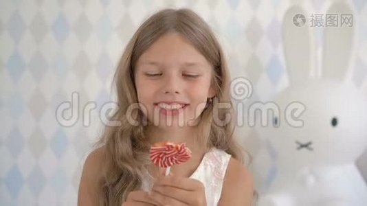 有趣的孩子带着糖果棒棒糖，快乐的小女孩吃棒棒糖，孩子在家吃糖果视频