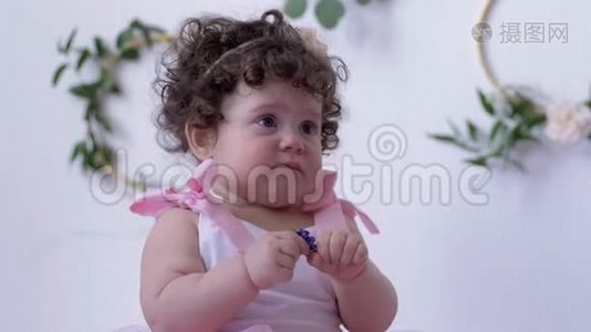 穿着粉色连衣裙、手中拿着一朵花在摄影棚特写镜头上拍照的婴儿视频