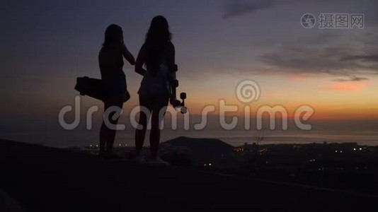 女朋友在山顶上玩滑板后看日落的美丽景色视频