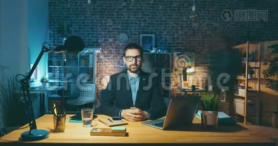 帅哥坐在办公室办公桌旁看着摄像机的延时肖像视频