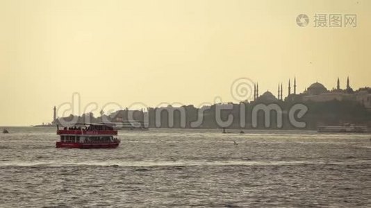 红色旅游步行船在博斯普鲁斯海峡，以伊斯坦布尔银行与历史建筑。 动作慢，全视频