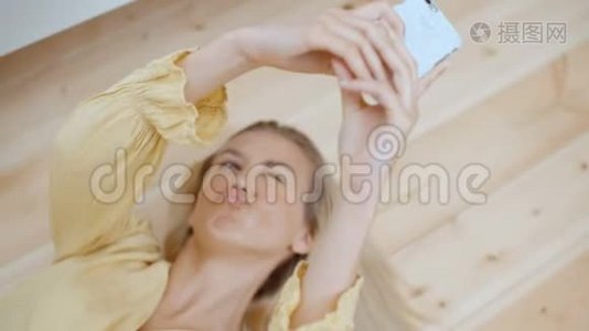 年轻的金发女人躺在地板上自拍。视频