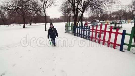 一个快乐的男孩在雪地上和孩子们一起跑`挥手视频