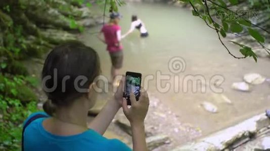 一位女士用智能手机拍摄两个女孩的照片视频