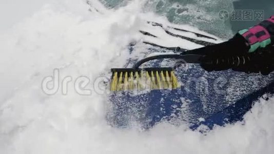 女人用刷子积极地清除冬天雪中的车罩视频