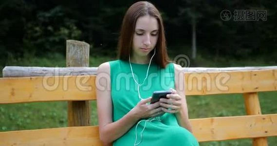 年轻女子躺在长凳上，用耳机听音乐。视频