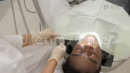 女牙医治疗病人。 年轻的非裔美国男性病人在牙科诊所的椅子上。 医学、卫生视频